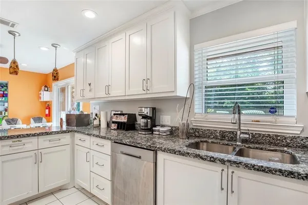 a kitchen with granite countertop a sink window and cabinets