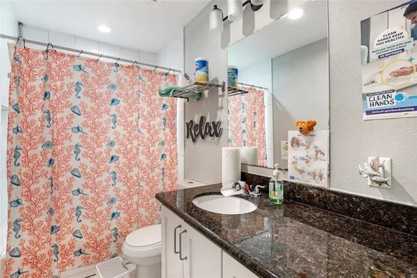 a bathroom with a granite countertop sink a toilet and a shower curtain