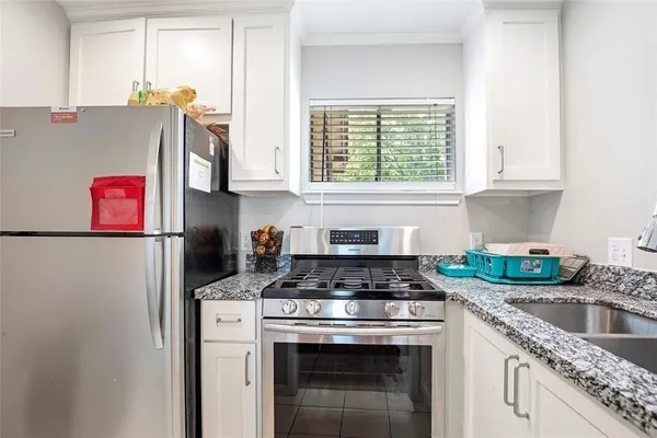 a kitchen with granite countertop a stove sink and cabinets