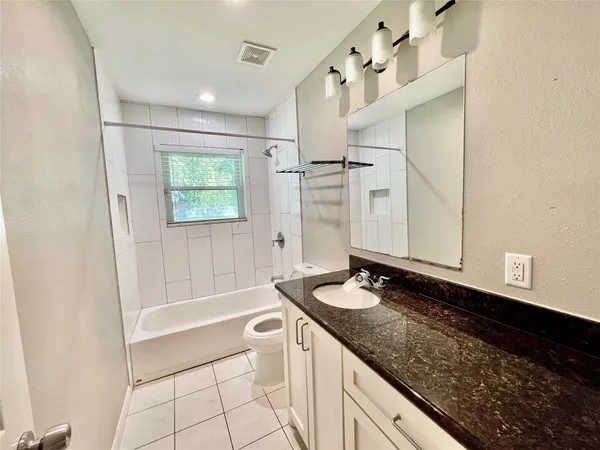 a bathroom with a granite countertop sink a toilet and shower