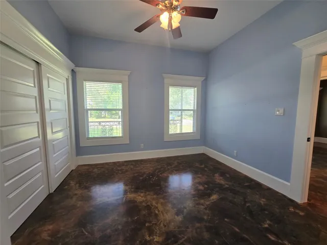 an empty room with wooden floor fan and window