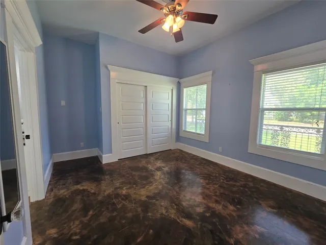 an empty room with windows and chandelier fan