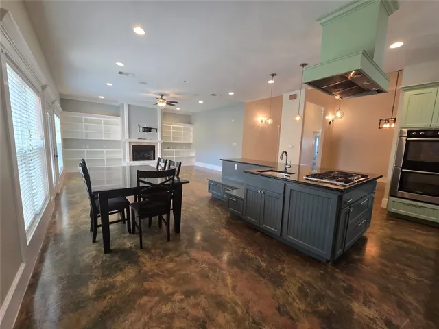 a kitchen with stainless steel appliances kitchen island granite countertop a table chairs sink and stove top oven
