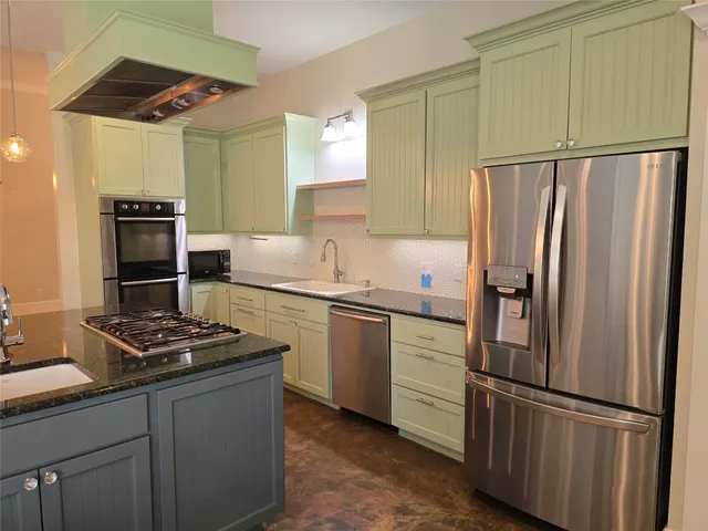 a kitchen with stainless steel appliances granite countertop a refrigerator and a stove