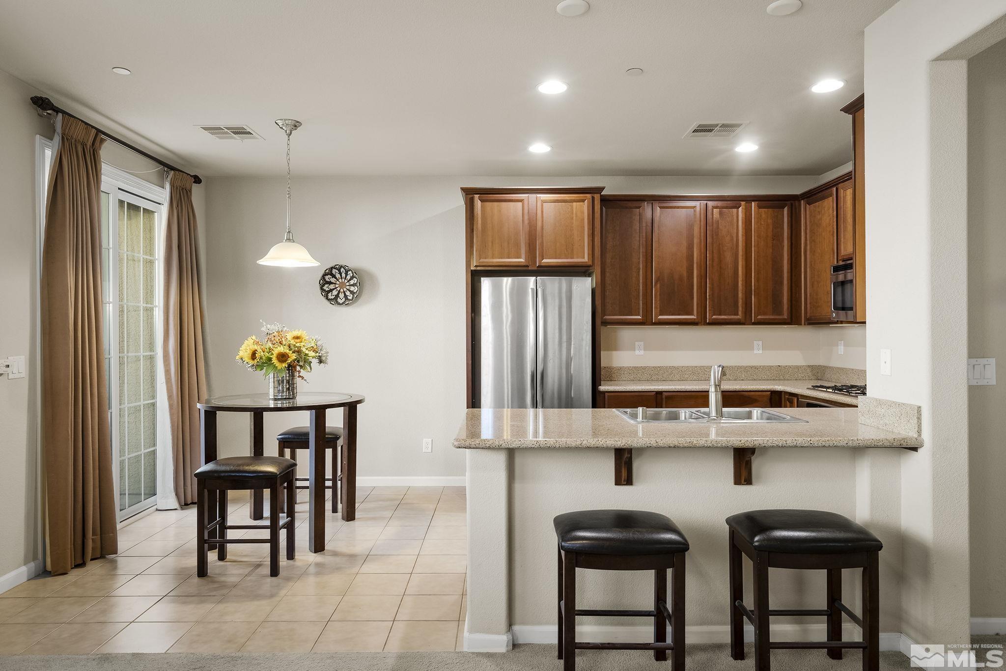 1925 Wind Ranch Road, Unit A Reno, NV 89521 - Photo 8 of 21 a kitchen with stainless steel appliances granite countertop a stove top oven a refrigerator a dining table and chairs with wooden floor