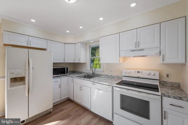 a kitchen with granite countertop white cabinets and white appliances