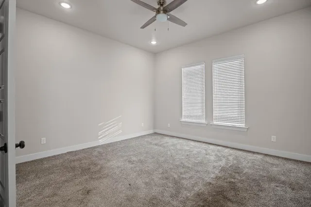 an empty room with a ceiling fan and a window