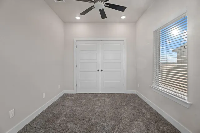 an empty room with windows and fan