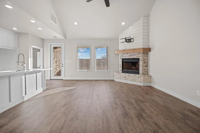 an empty room with wooden floor fireplace and windows