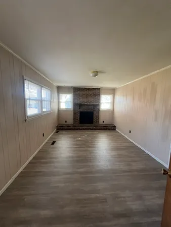 an empty room with windows and fireplace