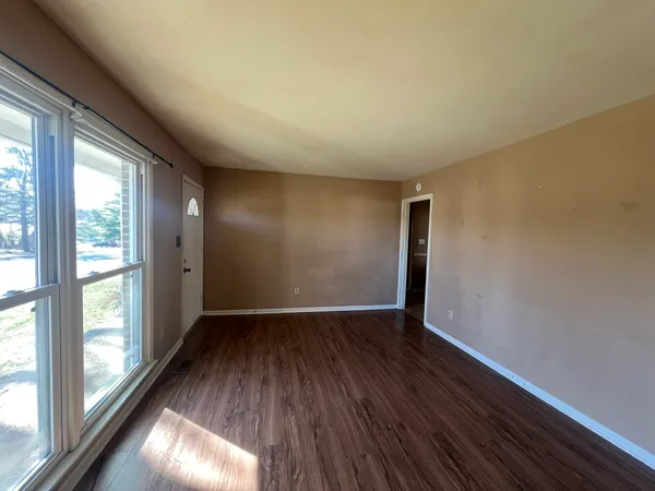 a view of an empty room with wooden floor and a window