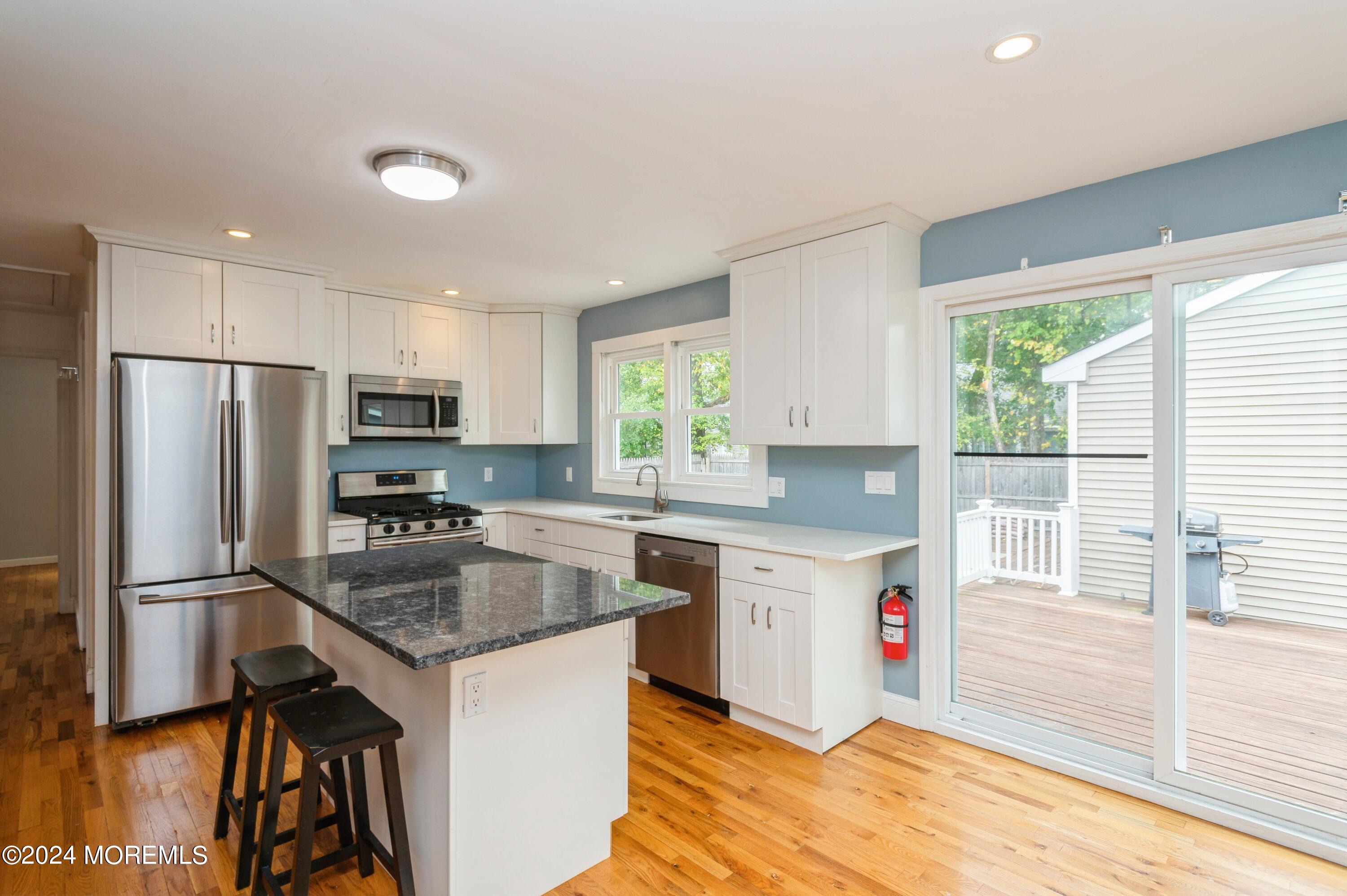 19 Holly Road Brick, NJ 08723 - Photo 6 of 16 a kitchen with a refrigerator a sink dishwasher a stove and white cabinets with wooden floor