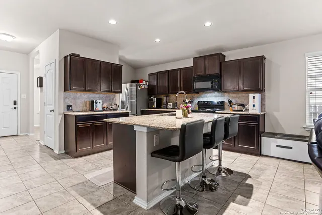 a kitchen with kitchen island granite countertop a stove sink microwave and cabinets