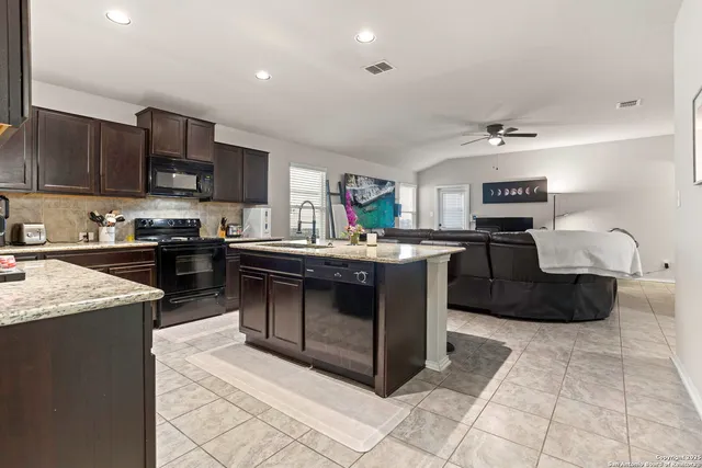 a kitchen with kitchen island granite countertop a sink dishwasher stove and cabinets
