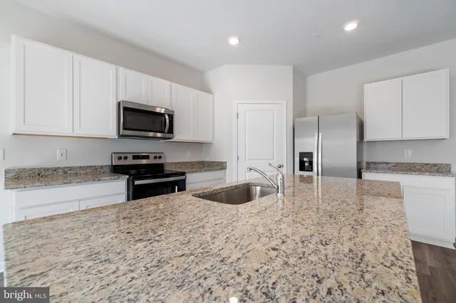 a kitchen with stainless steel appliances granite countertop a sink a stove and a refrigerator