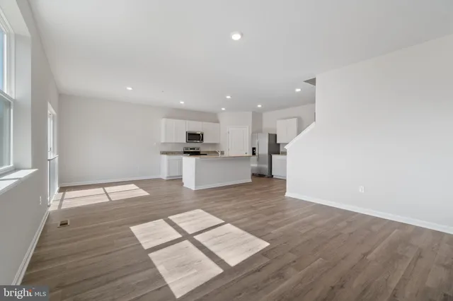 a large white kitchen with wooden floors and stainless steel appliances