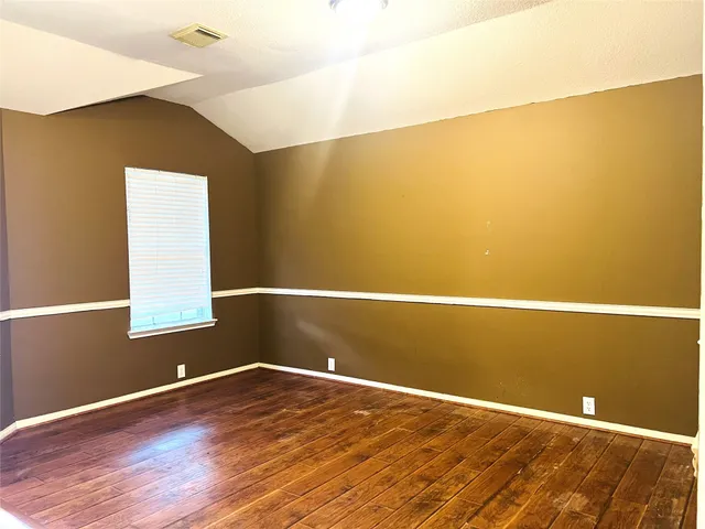 a view of a big room with wooden floor and windows
