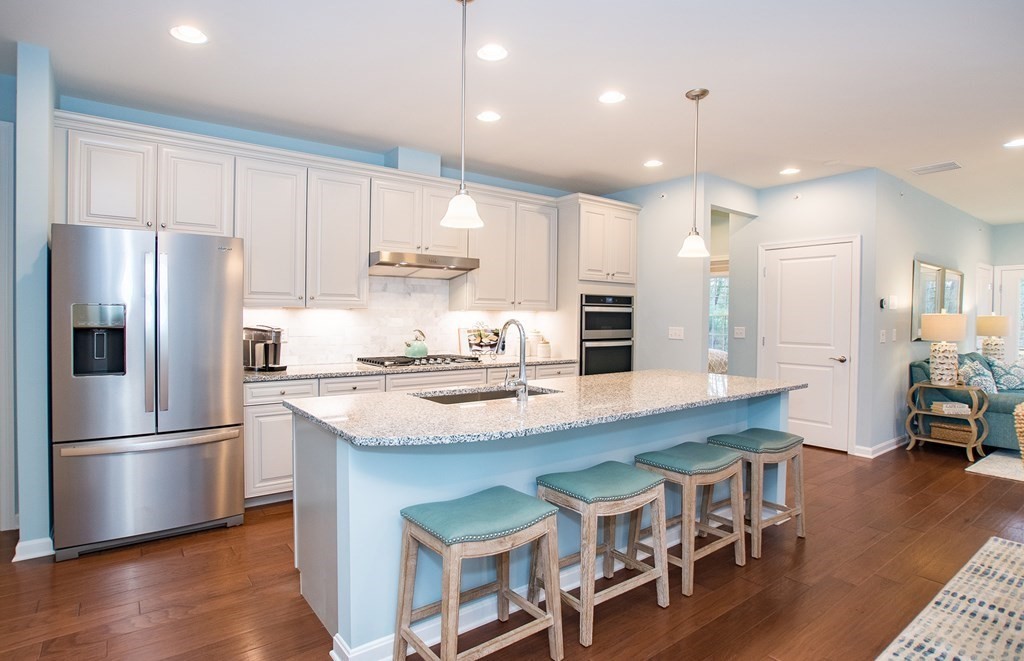 a kitchen with stainless steel appliances granite countertop a table chairs refrigerator and sink