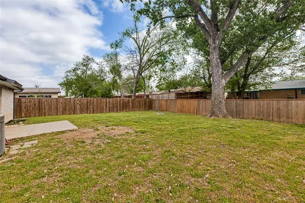 a view of a backyard with large tree and wooden fence
