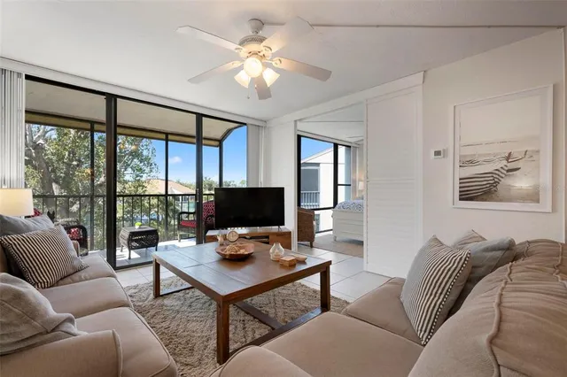 a living room with furniture a flat screen tv and a floor to ceiling window