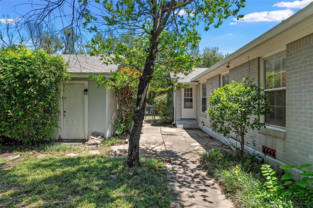 3225 Windsor Avenue Waco, TX 76708 - Photo 18 of 25 Exterior pathway leading to a rear entrance, flanked by a brick-clad structure and a detached utility shed