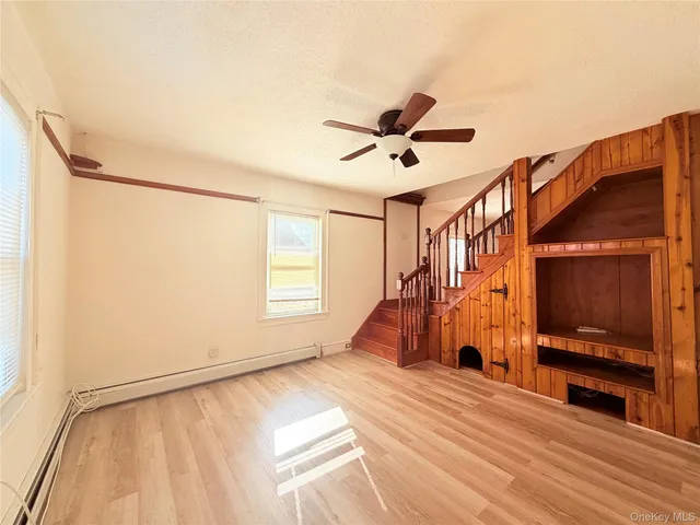 a view of empty room with wooden floor and fan