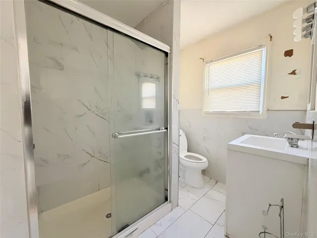 a bathroom with a granite countertop sink a toilet and shower