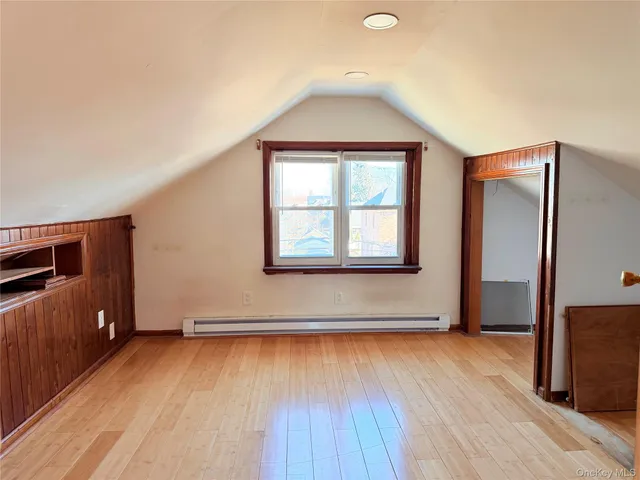 an empty room with wooden floor closet and windows