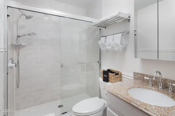 a bathroom with a granite countertop bathtub shower sink vanity and toilet
