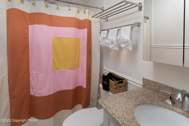 a bathroom with a granite countertop toilet sink and mirror