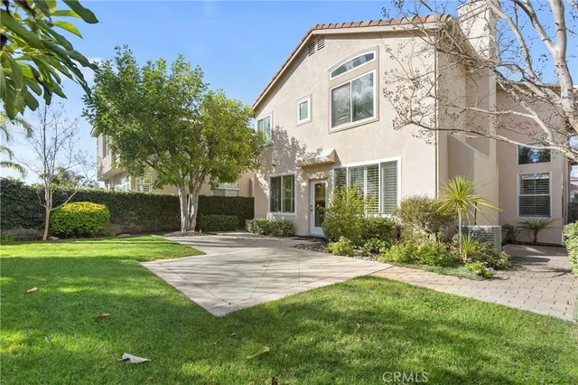 a view of a white house next to a yard with plants and trees