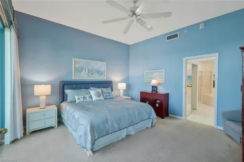 a bedroom with a bed a dresser and a large window