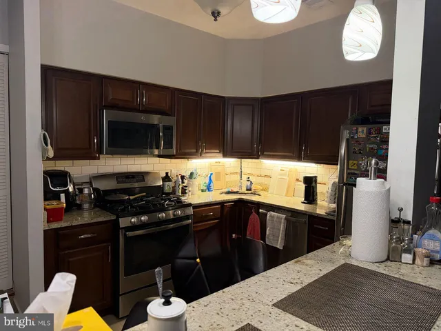 a kitchen with stainless steel appliances granite countertop a sink dishwasher stove top oven and cabinets with wooden floor
