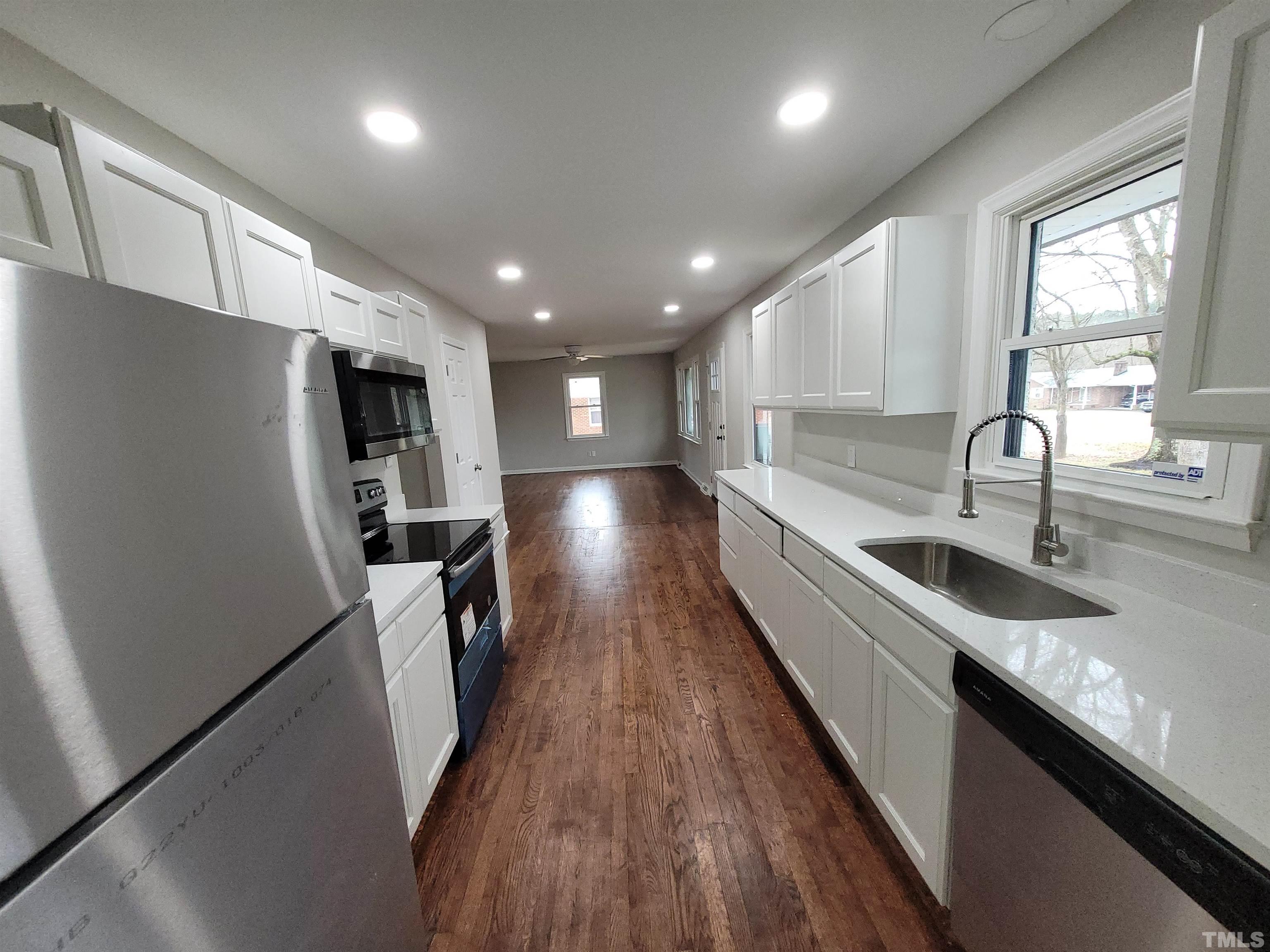 a large kitchen with stainless steel appliances a sink a refrigerator and a counter top space