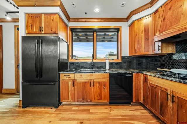 a kitchen with stainless steel appliances granite countertop a refrigerator a stove and a sink