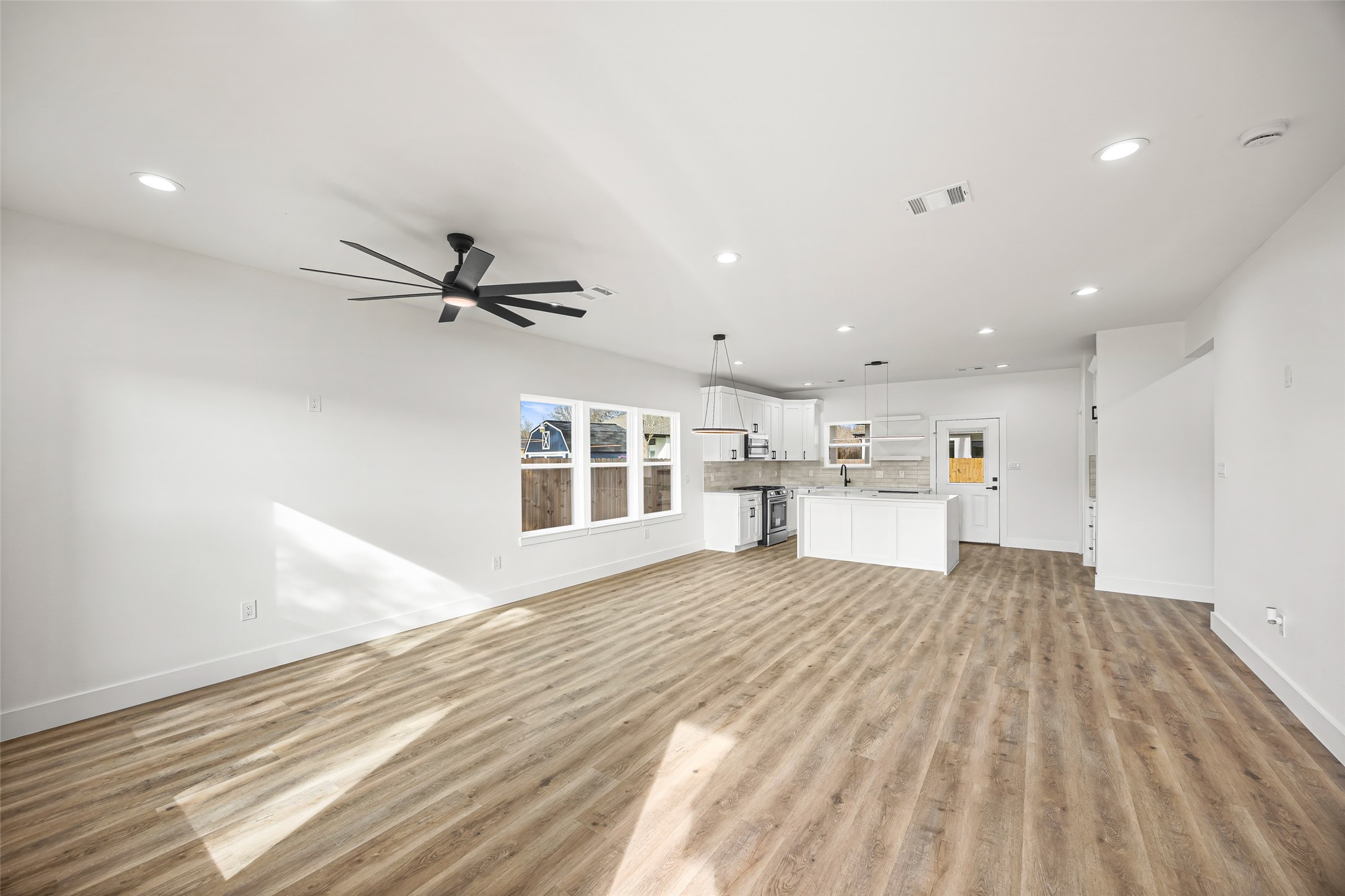 1807 Waco Street Dayton, TX 77535 - Photo 3 of 26 Bright and expansive open-concept living space with luxury vinyl plank flooring, recessed lighting, and modern ceiling fan.