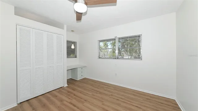 a view of empty room with wooden floor and fan