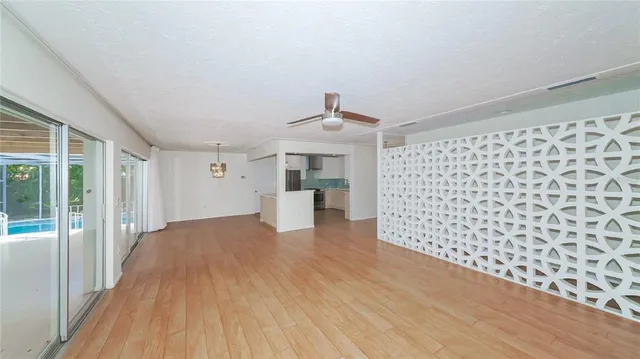 a view of empty room with wooden floor and fan