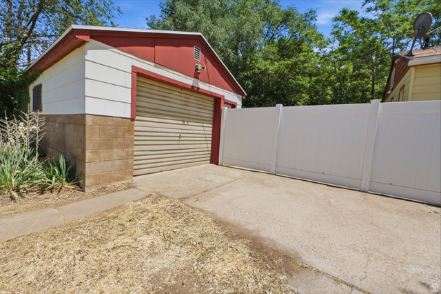 94 West 2000th Street North Clearfield, UT 84015 - Photo 20 of 26 Detached garage with roll-up door, concrete driveway, and enclosed yard access.