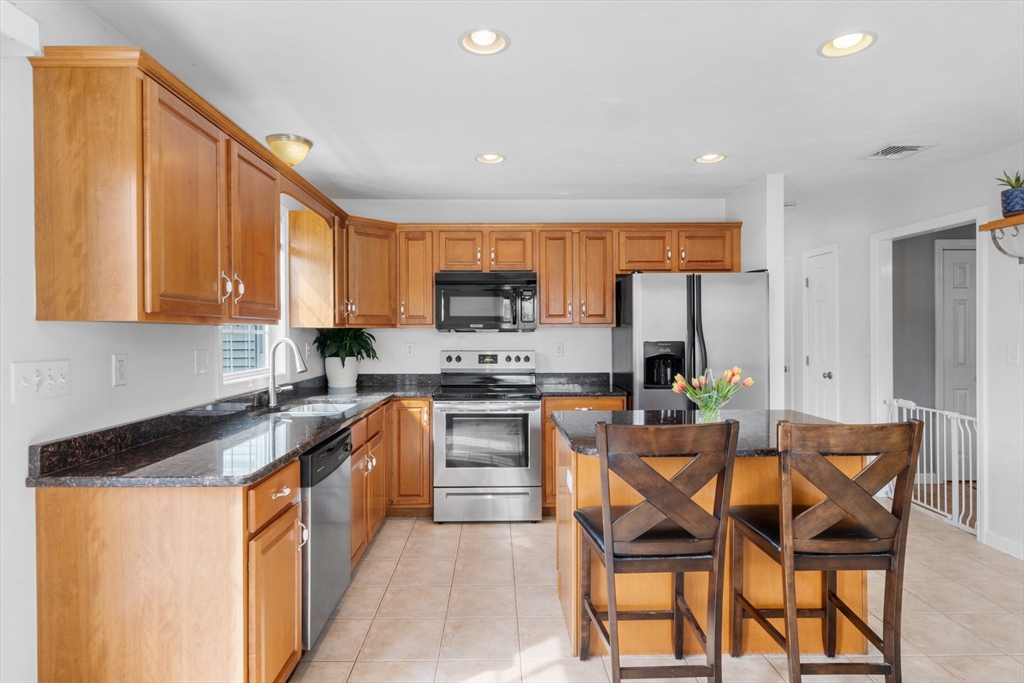 12 Pinckney Street, Unit A Taunton, MA 02780 - Photo 5 of 42 a kitchen with stainless steel appliances granite countertop a refrigerator a stove a sink a dining table and chairs with wooden floor