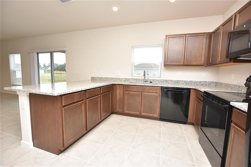 622 Manchester Path Dundee, FL 33838 - Photo 3 of 46 a kitchen with stainless steel appliances granite countertop wooden cabinets a sink and dishwasher