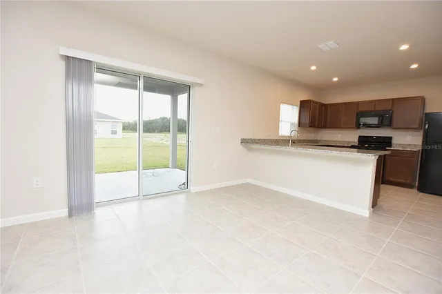 a view of kitchen with stainless steel appliances granite countertop a stove and a sink