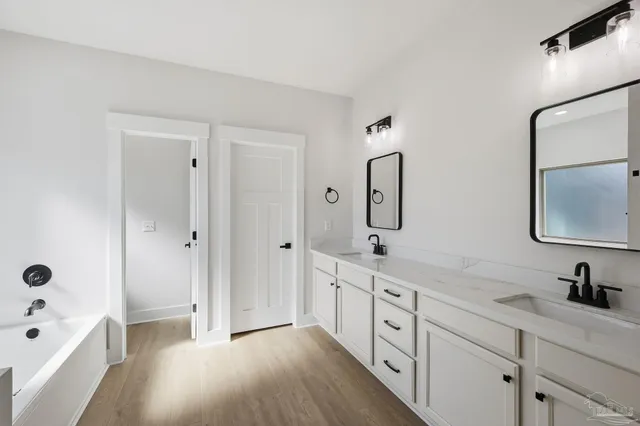 a spacious bathroom with a double vanity sink a mirror and a bathtub