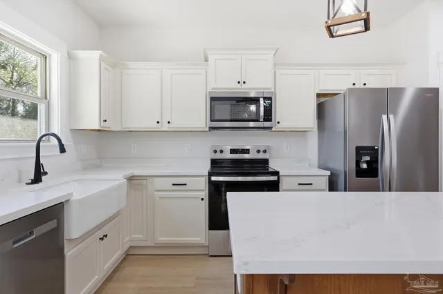a kitchen with stainless steel appliances a refrigerator sink and white cabinets