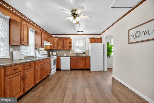 a kitchen with kitchen island wooden floors appliances and cabinets