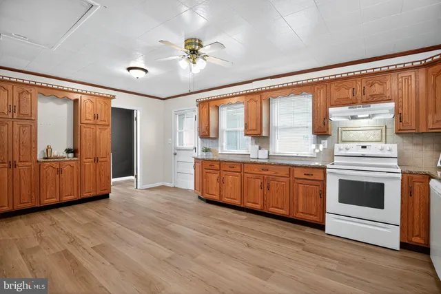 a kitchen with stainless steel appliances wooden floor and white cabinets