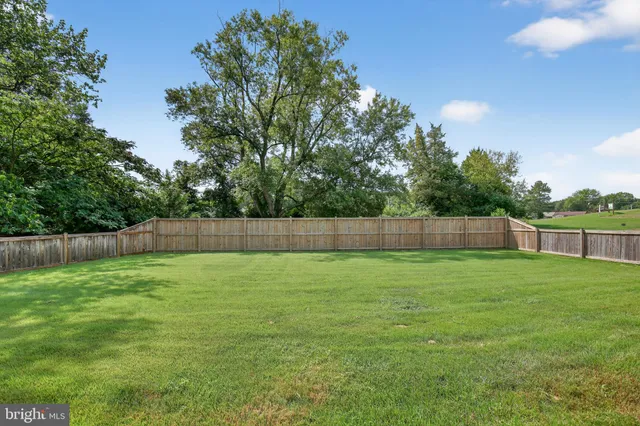 a view of a yard with a fence and trees