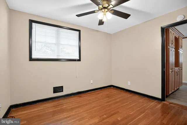 an empty room with wooden floor chandelier fan and windows