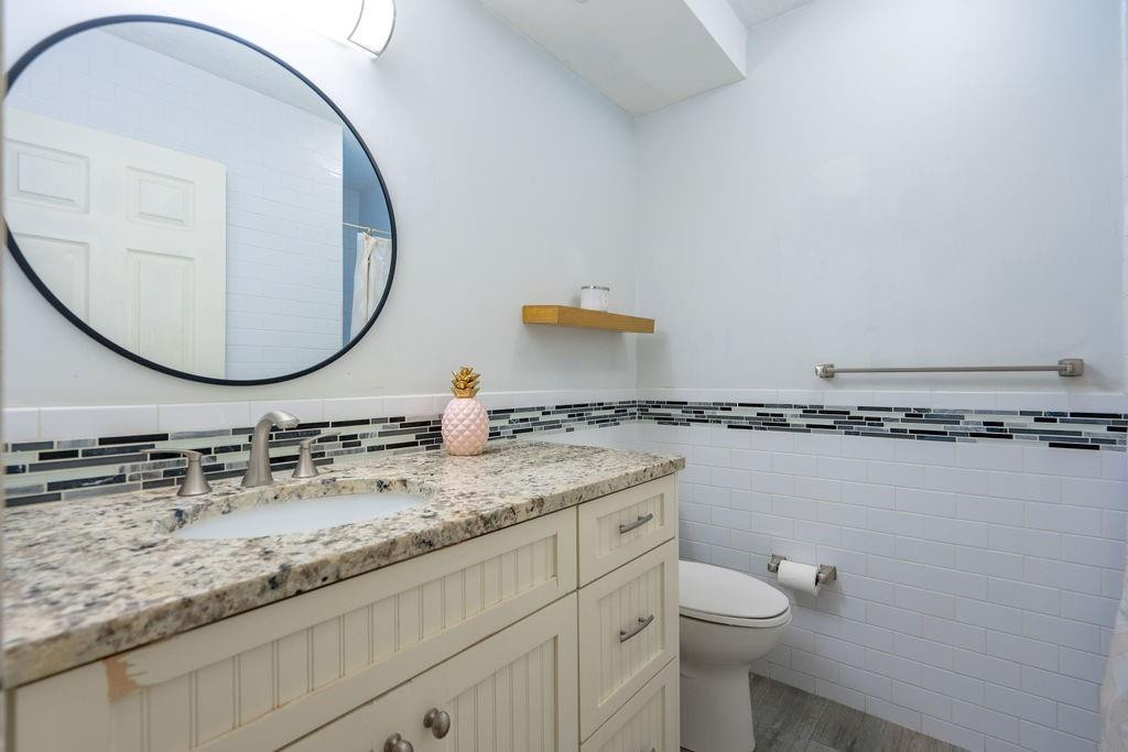 463 Newcastle Street Boca Raton, FL 33487 - Photo 15 of 32 a bathroom with a granite countertop toilet a sink and mirror