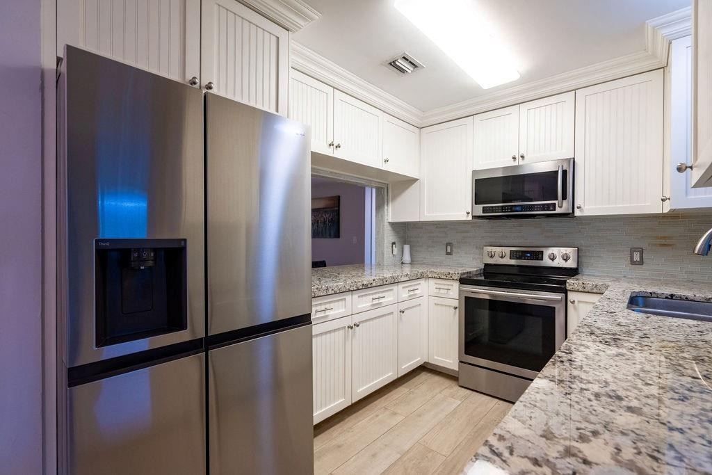 463 Newcastle Street Boca Raton, FL 33487 - Photo 10 of 32 a kitchen with stainless steel appliances granite countertop a refrigerator stove and microwave